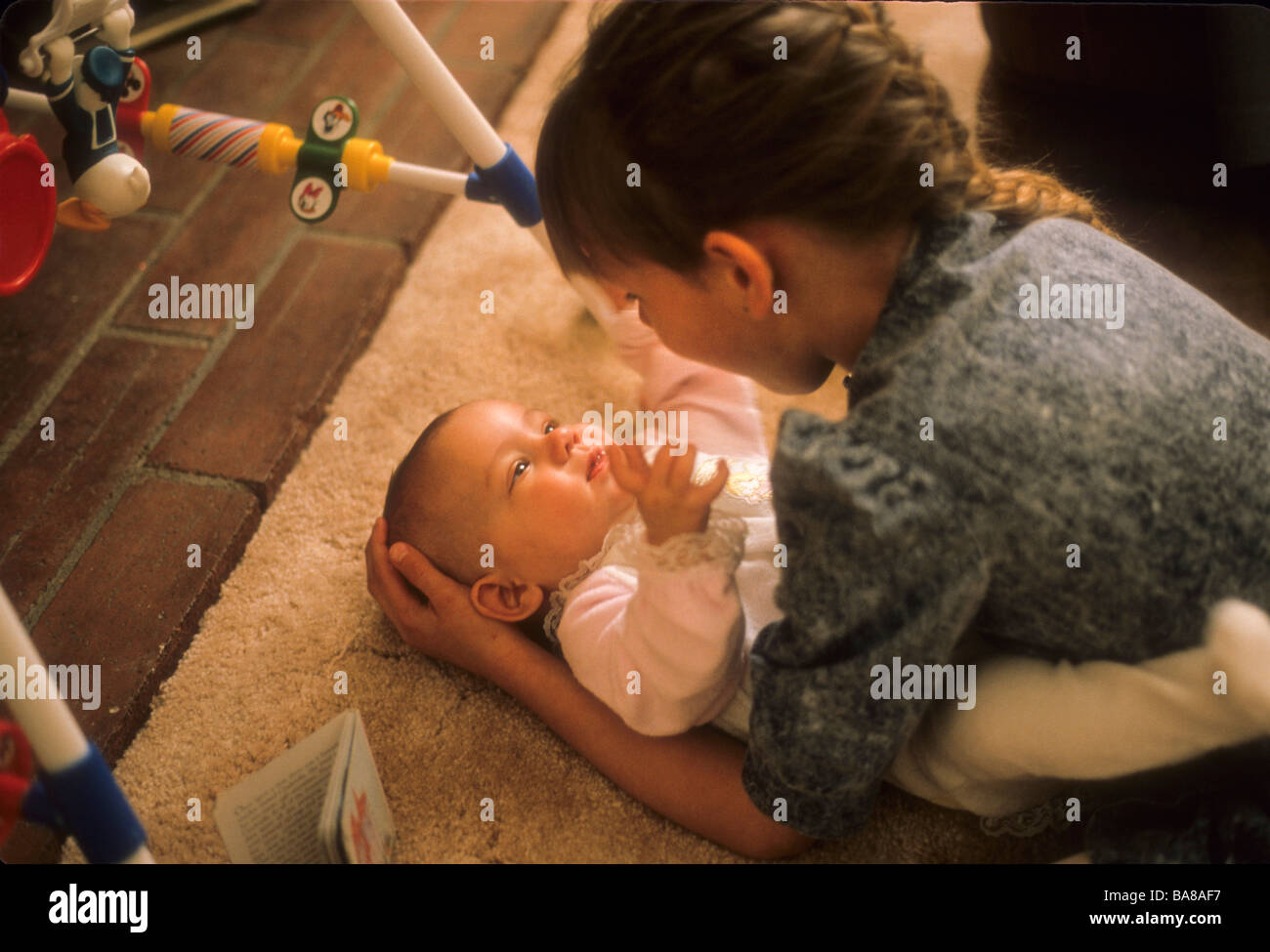 Girl jouer avec les plus jeunes baby sister la faisant sourire heureux joie amour fille enfant soins hug Banque D'Images