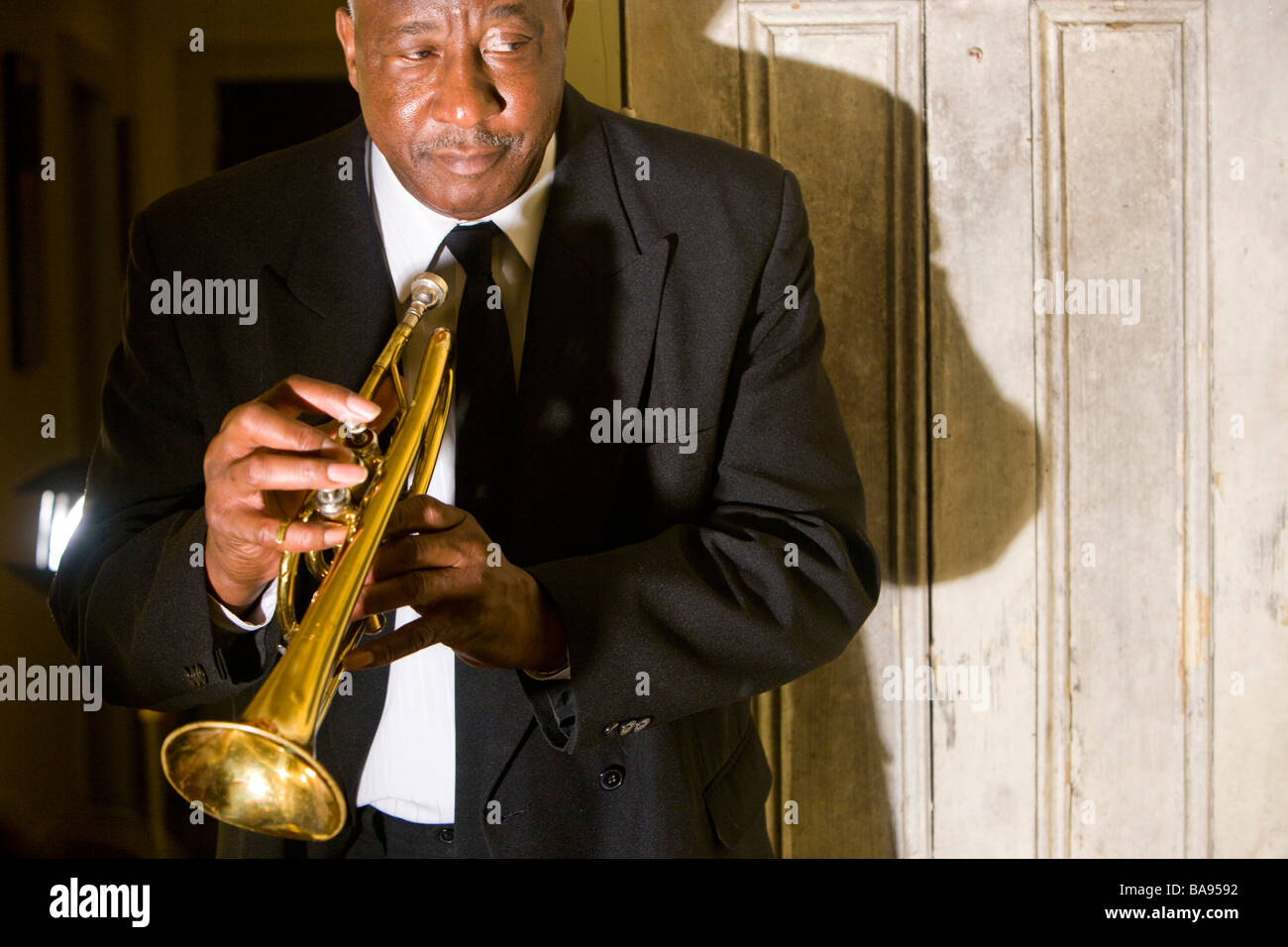 Senior African American musician holding trumpet, située près de la porte Banque D'Images