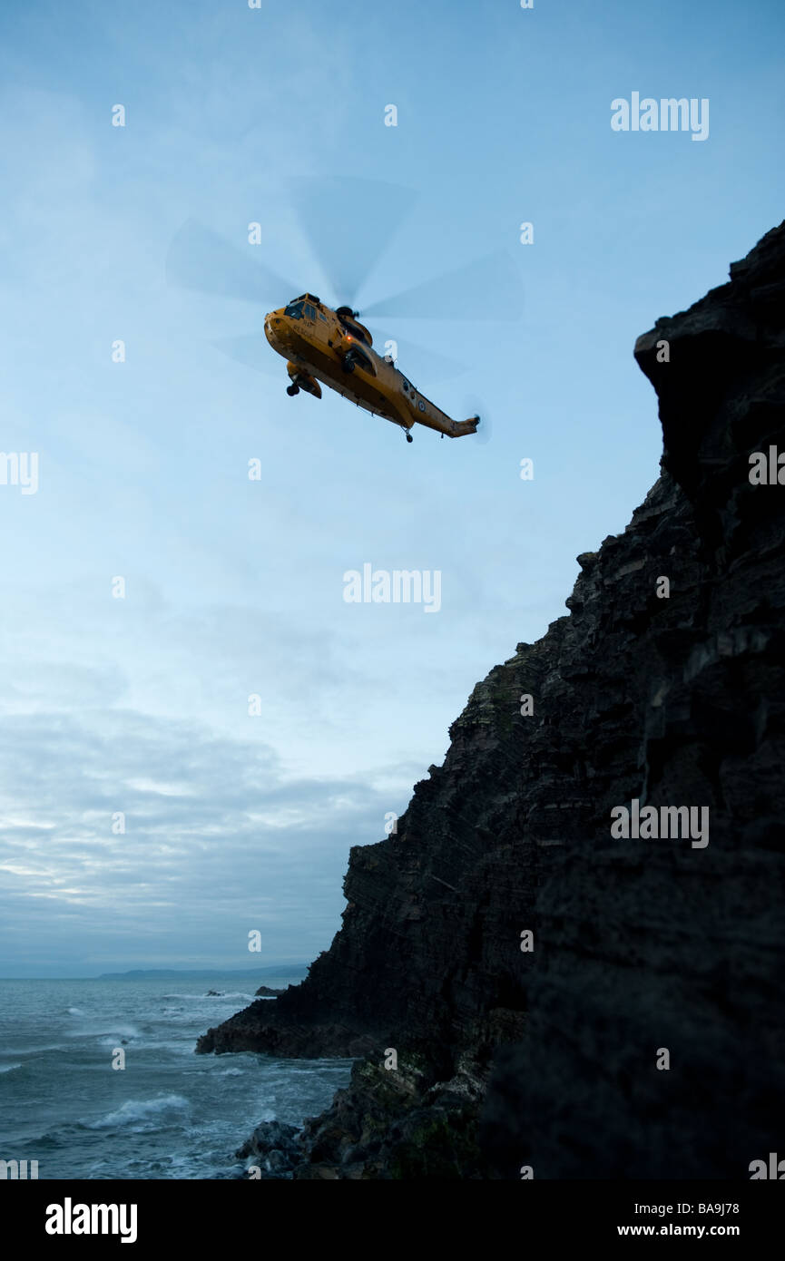 Un hélicoptère Sea King, le sauvetage d'un jeune homme qui avait perdu sa place sur les falaises à l'ouest du pays de Galles Aberystwyth UK at Dusk Banque D'Images