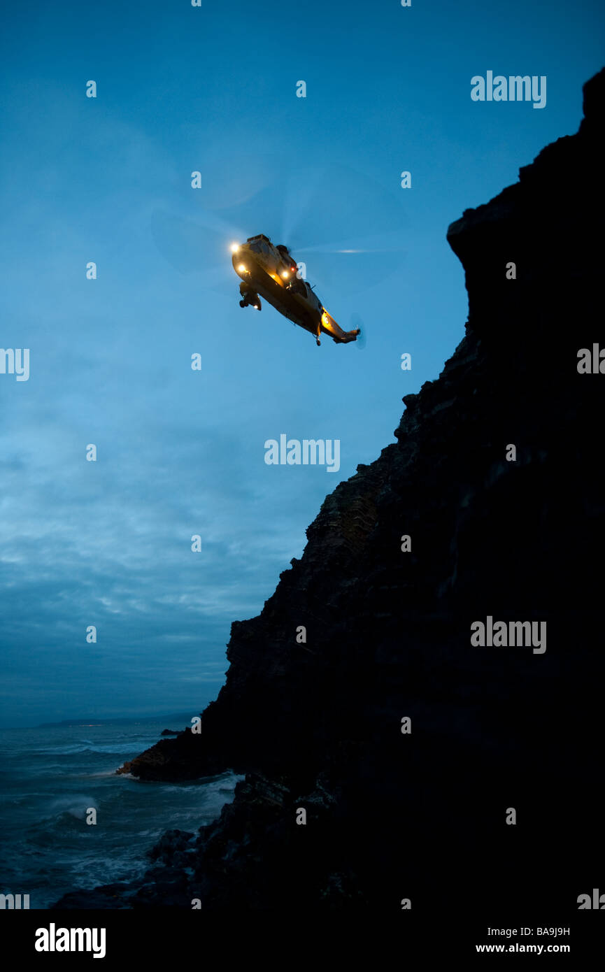 Un hélicoptère Sea King de la RAF Valley le sauvetage d'un jeune homme qui avait perdu sa place sur les falaises à l'ouest du pays de Galles Aberystwyth UK at Dusk Banque D'Images