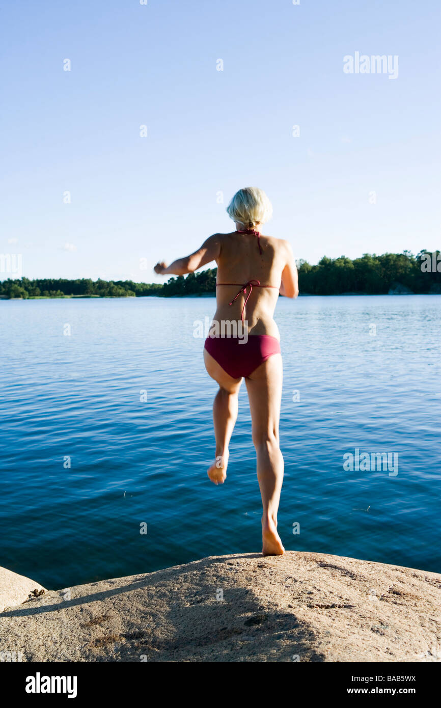 Une femme d'un saut d'une falaise dans l'archipel de Stockholm, Suède. Banque D'Images