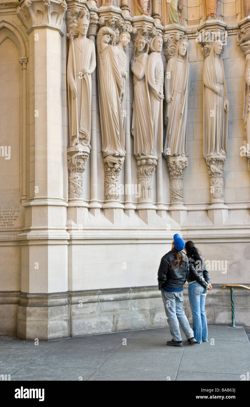 Les visiteurs d'admirer des sculptures sur la façade de la cathédrale de Saint John the Divine à New York City Banque D'Images