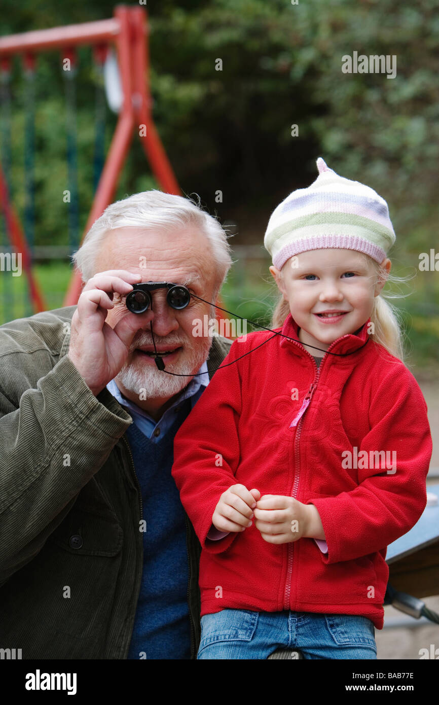 Grand-père et le petit-enfant regardant à travers des jumelles, la Suède. Banque D'Images