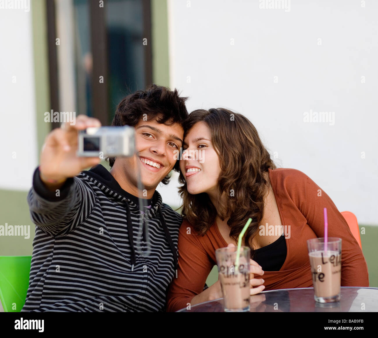 Un jeune couple assis à un café, holding a camera au Portugal. Banque D'Images