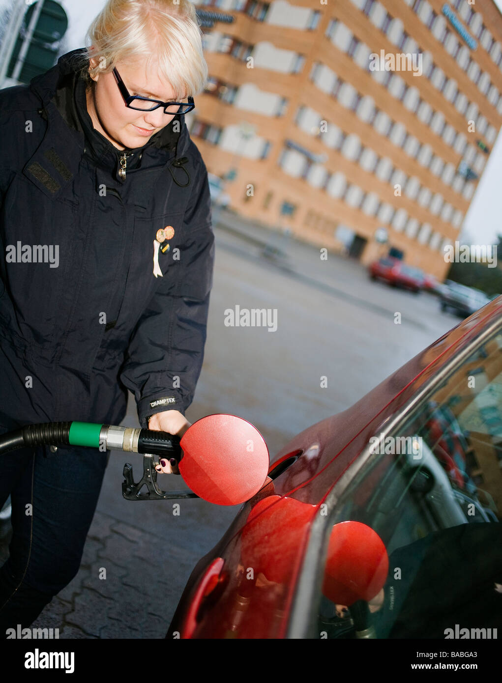 Une jeune femme scandinave de remplir le réservoir d'une voiture en Suède Banque D'Images