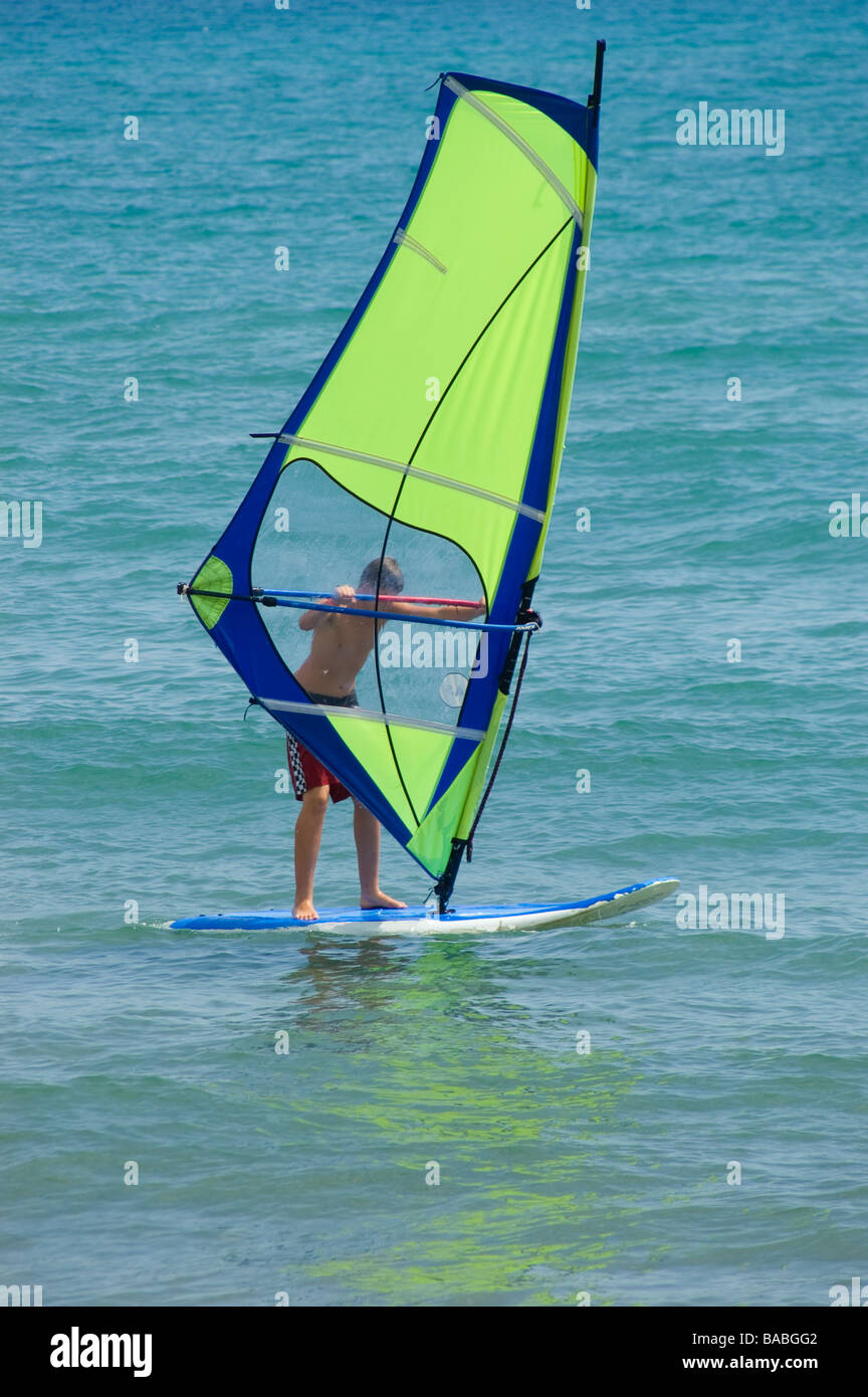 Planche à voile hommes avec un voile vert vif sur la magnifique mer turquoise avec réflexion Banque D'Images