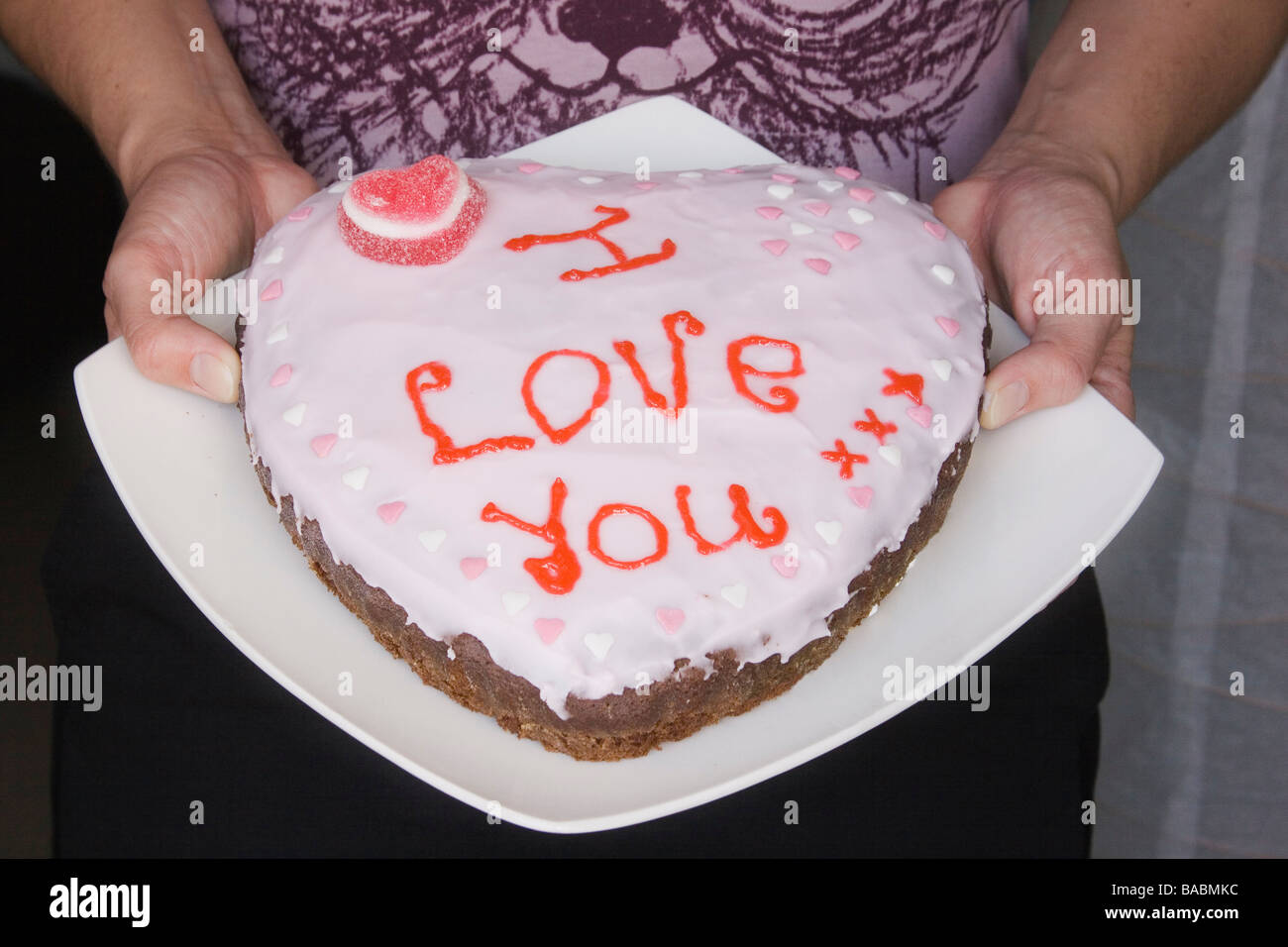 Femme Tenant Les Mains En Forme De Coeur Fait Maison Gateau Decore Avec Les Mots Je T Aime Ecrit En Glacage Rose Photo Stock Alamy