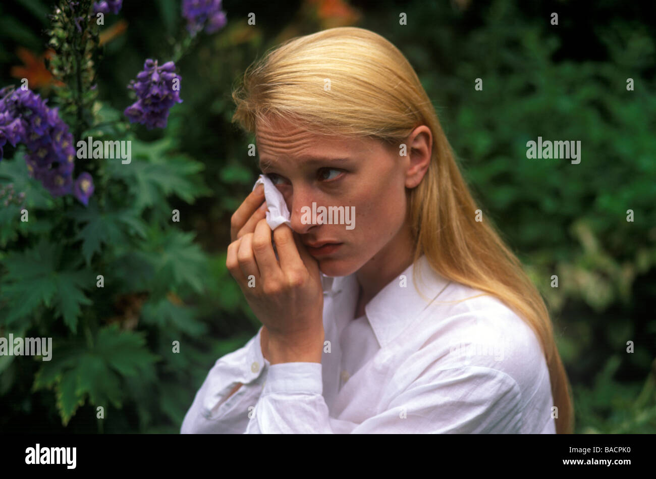 Femme dans le jardin se frotter les yeux à cause de la fièvre des foins Banque D'Images