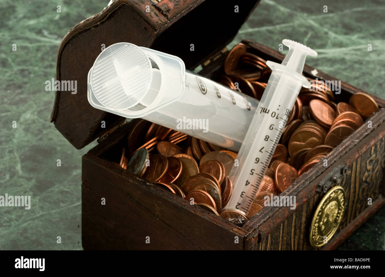 Deux des seringues en plastique collant dans un petit coffre au trésor rempli de pièces de monnaie Banque D'Images