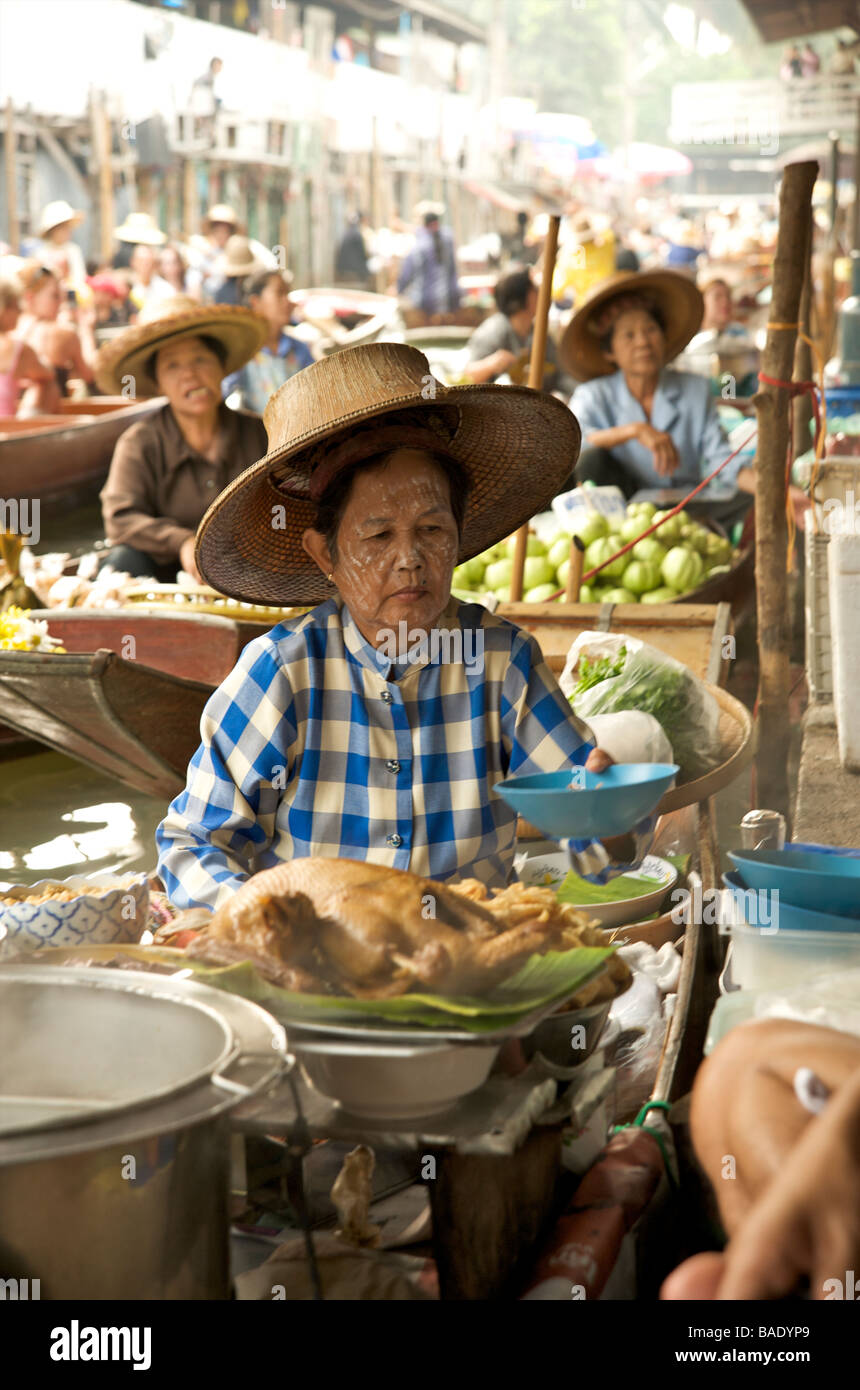 Une femme thaïlandaise servant un bol de soupe épicée chaude de son bateau au marché flottant très animé près de Bangkok Thaïlande Banque D'Images