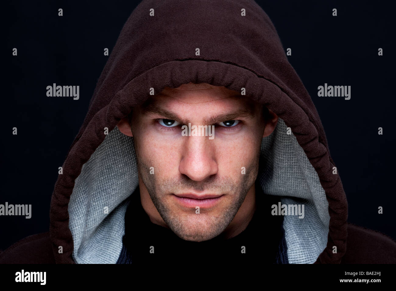 Portrait d'un homme portant un haut à capuchon brun avec un regard intense Banque D'Images