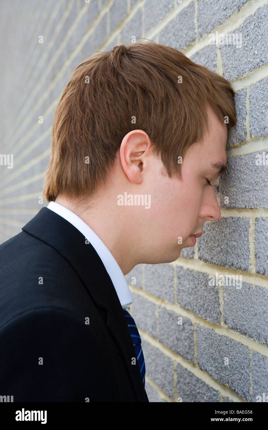 Businessman with head against brick wall Banque D'Images