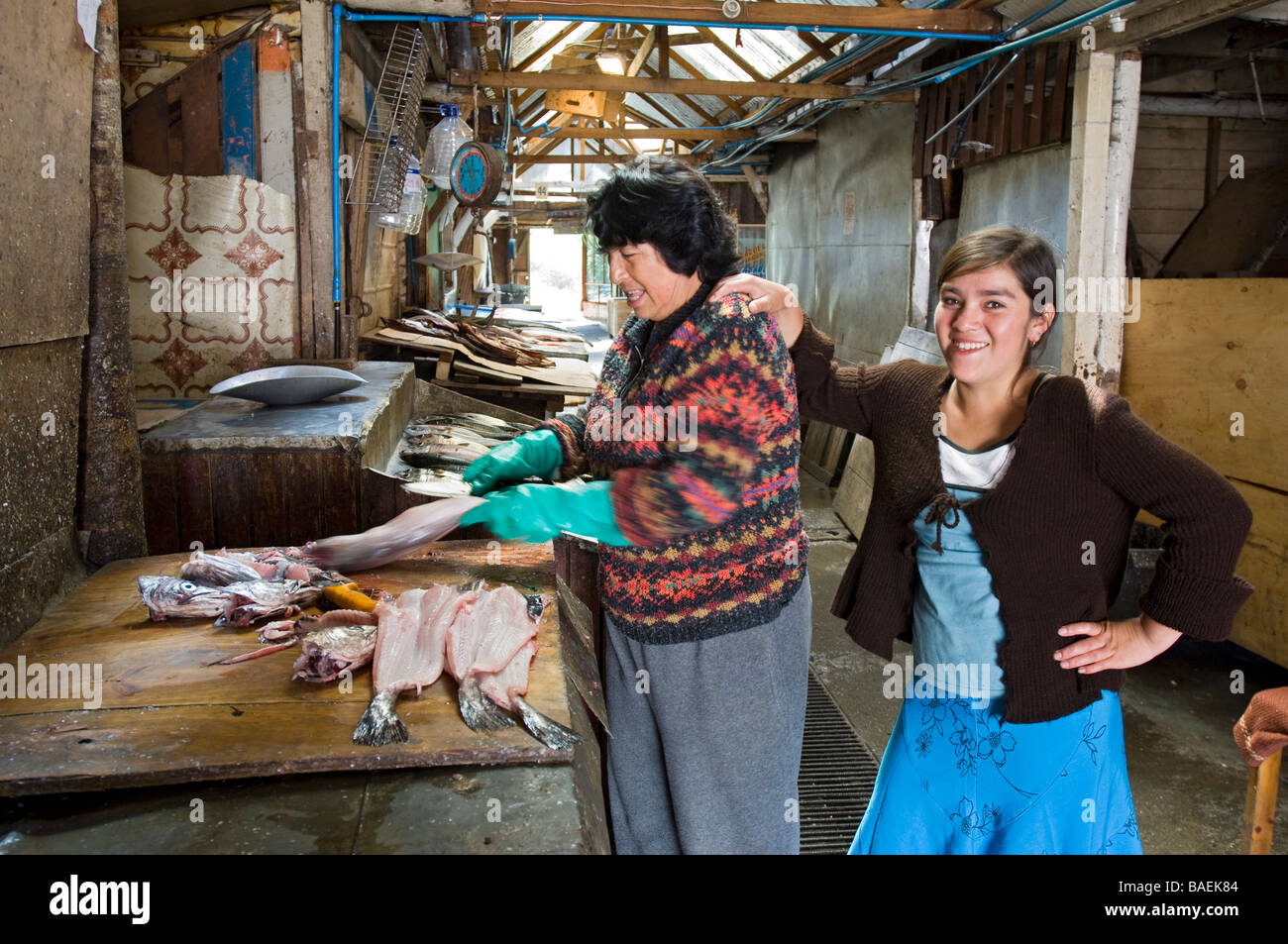 Mère et fille de préparer le saumon et les filets de poisson dans le marché artisanal. Puerto Montt, Chili. Banque D'Images