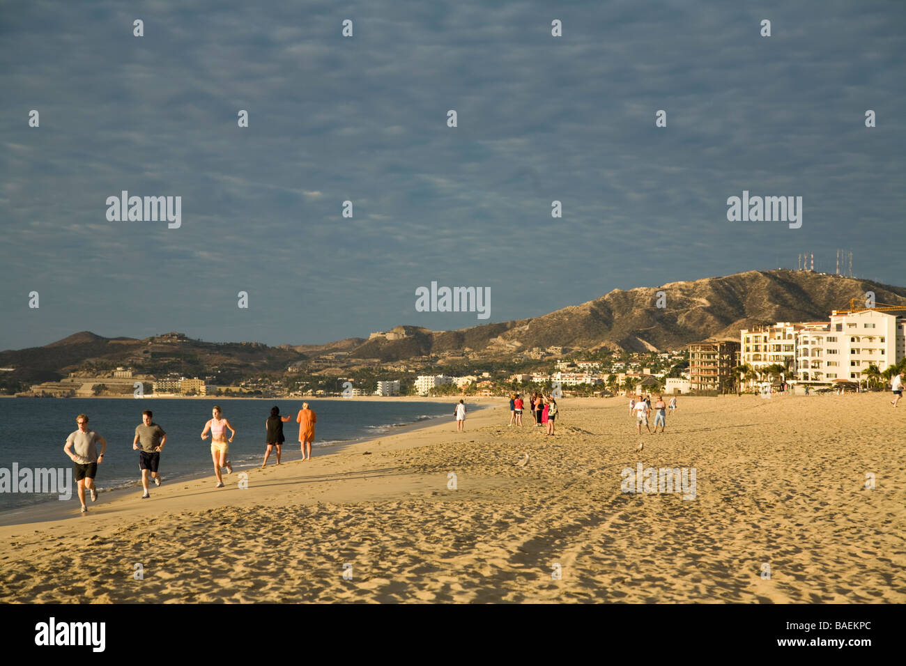 Mexique San Jose del Cabo Personnes à pied et flâner le long de la plage tôt le matin des bâtiments sur la colline Banque D'Images