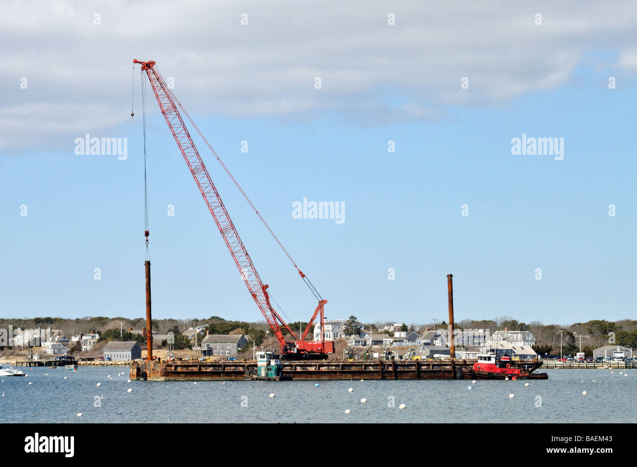 Grue rouge sur une barge d'entasser avec réglage de deux remorqueurs dans le port de 'STAGE' 'Chatham Cape Cod' Banque D'Images