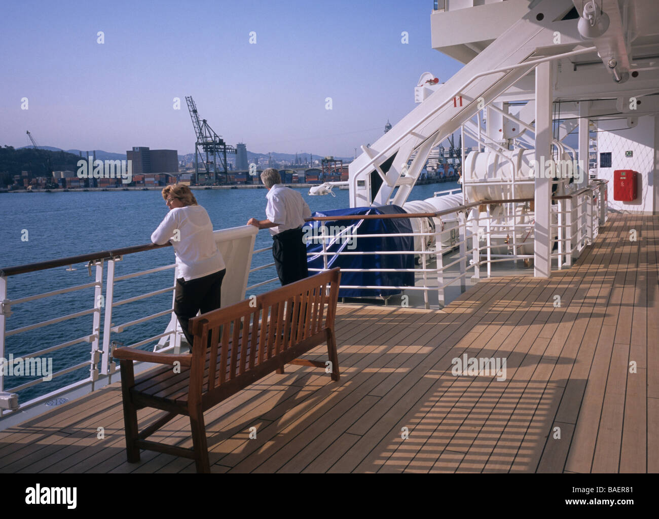 Couple de passagers s'appuyant sur les grilles d'un navire de croisière amarré dans le port de Barcelone Espagne Banque D'Images
