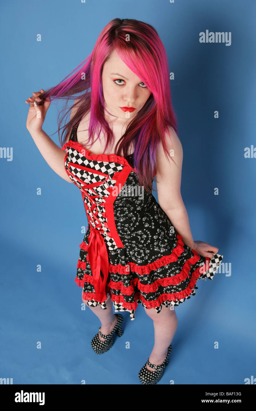 Portrait d'une belle jeune fille avec de longs cheveux roses peau pâle et rouge lèvres portant une robe rouge et noir. Banque D'Images