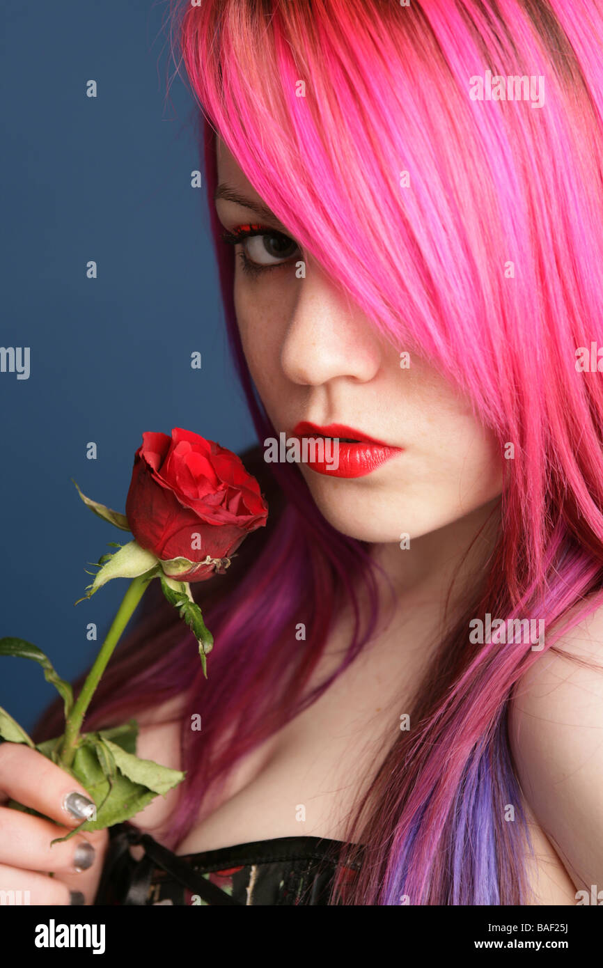 Portrait d'un jeune de 18 ans fille gothique avec des cheveux rose tenant une rose Banque D'Images