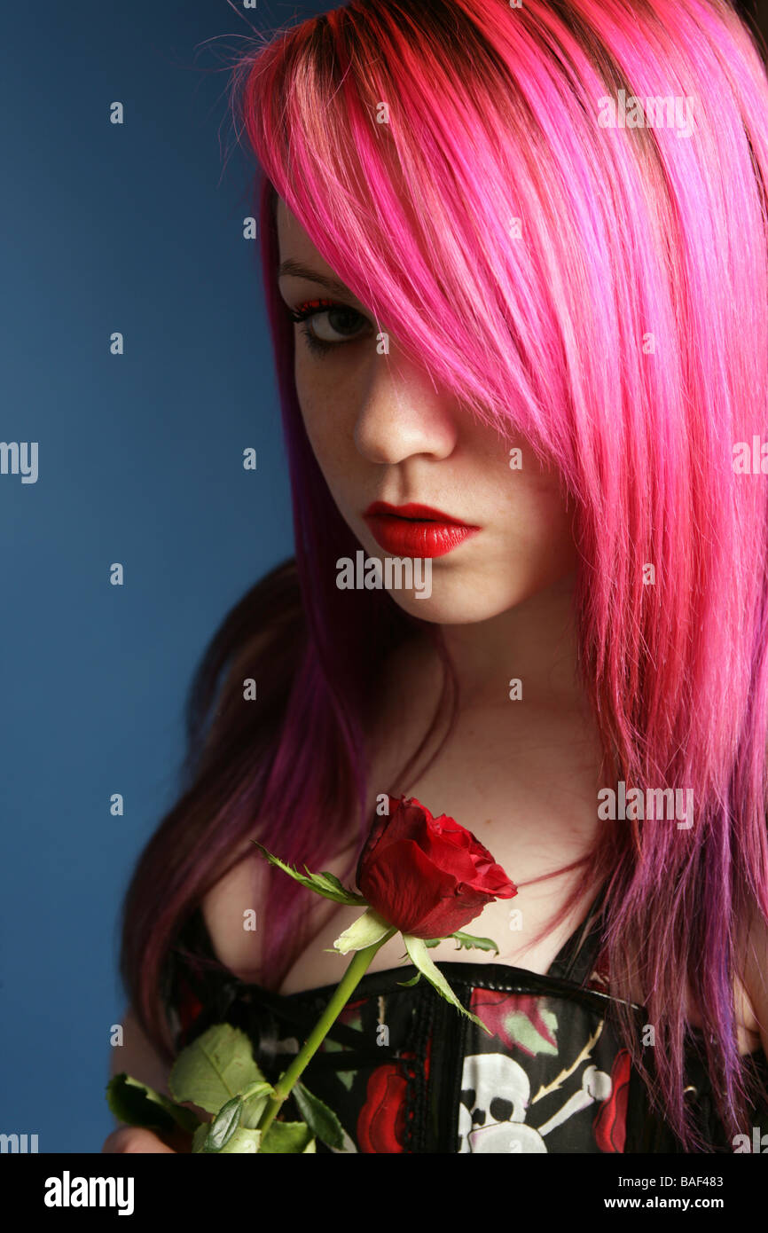 Portrait d'un jeune de 18 ans fille gothique avec des cheveux rose tenant une rose Banque D'Images