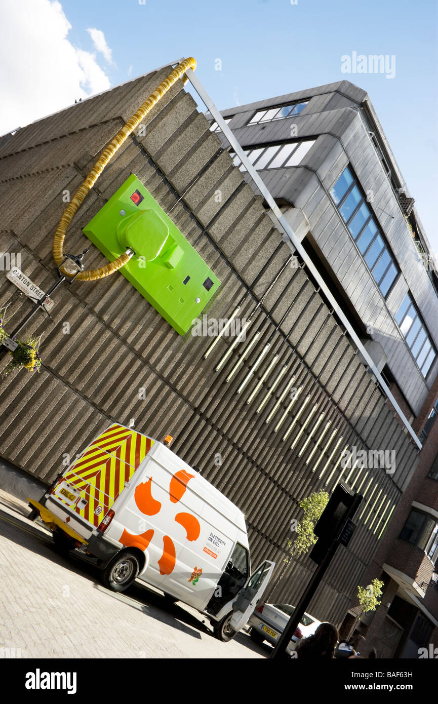 Réparation Électricité van à l'extérieur d'un bâtiment dans le centre de Londres. La construction semble avoir un géant et le socket sur son mur extérieur Banque D'Images