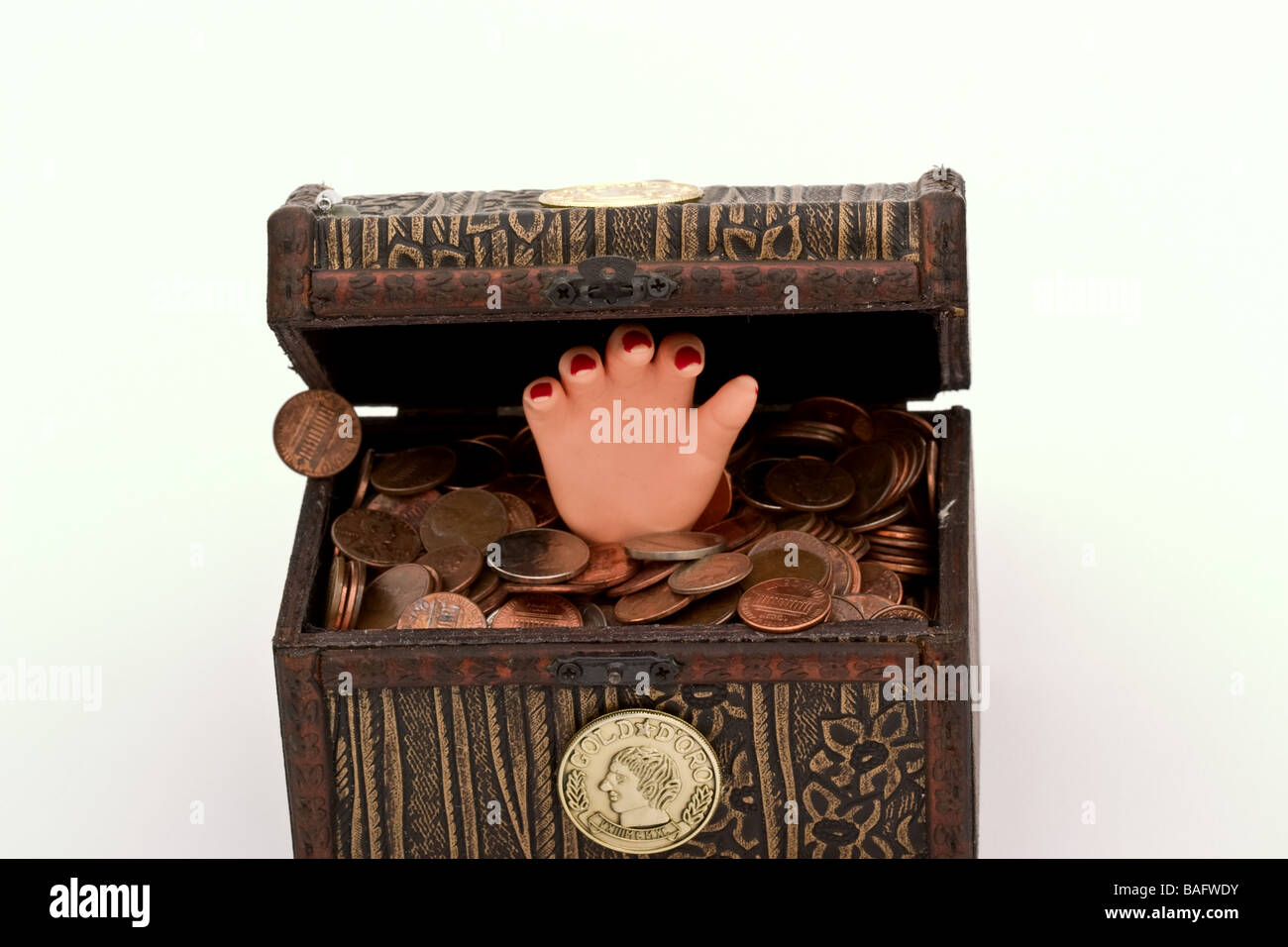 Petite main en plastique dans un petit coffre au trésor rempli de pièces de monnaie Banque D'Images