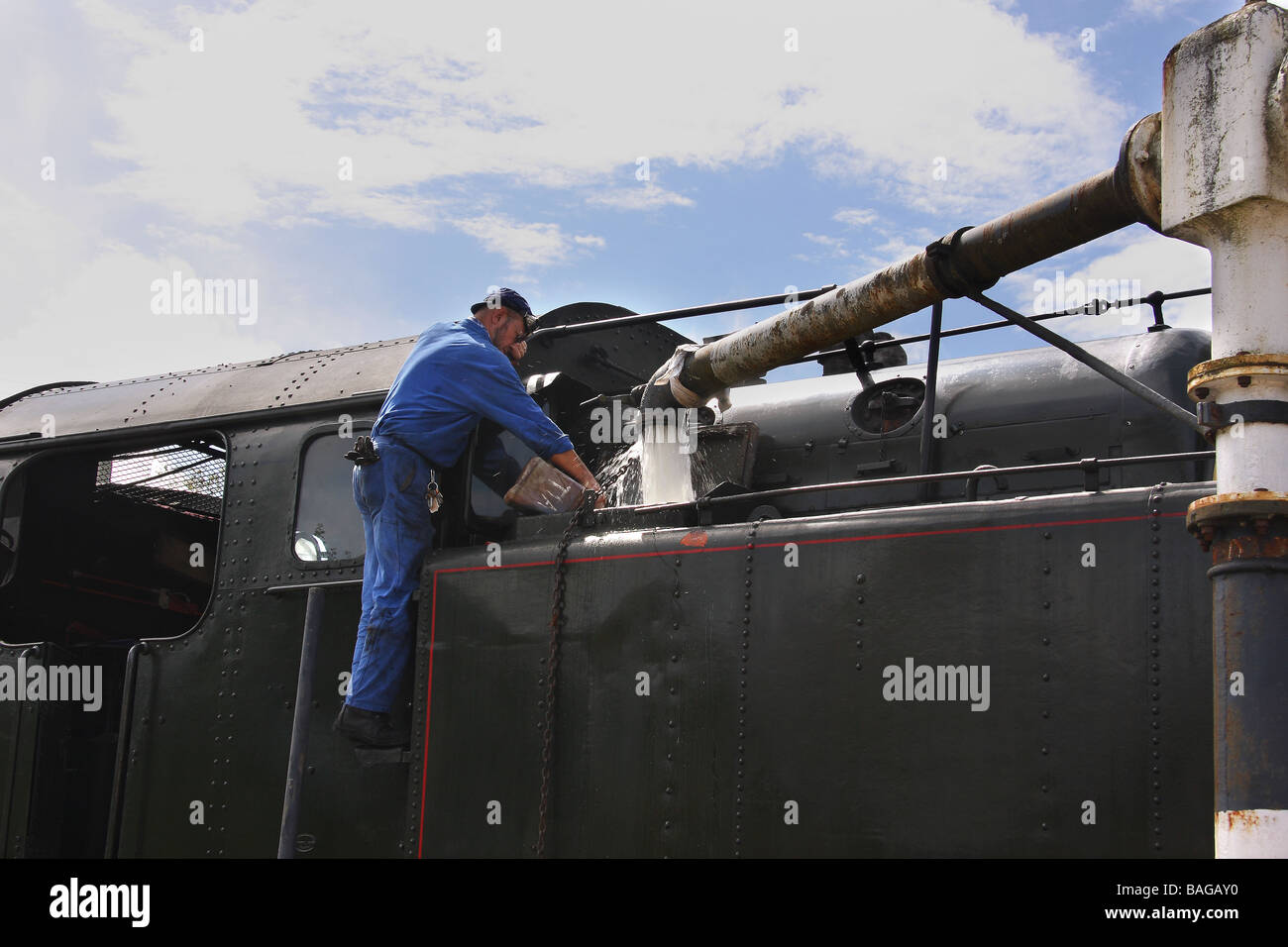 Un train à vapeur prend l'eau l'ingénieur verser dans un additif Limousin France Banque D'Images