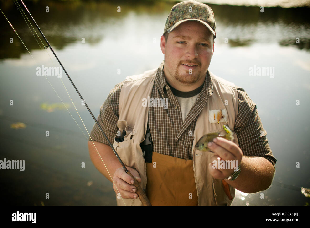 L'homme a l'air dégoûté de la stupide petit poisson qu'il vient de prendre sur son fancy pants des engins de pêche. Pourraient à peine faire un apéritif. Banque D'Images