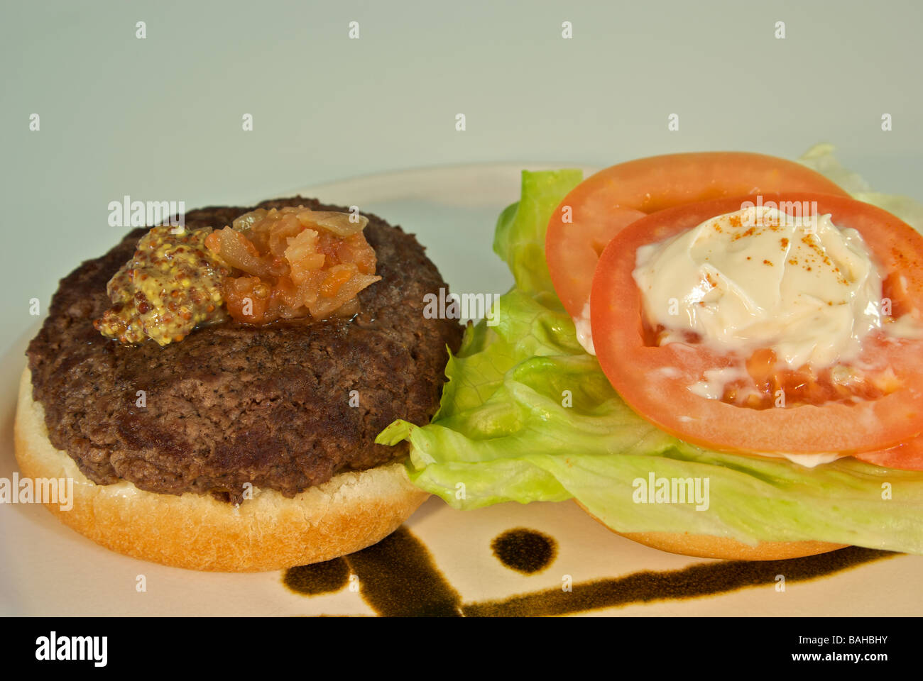 Hamburger de luxe relish tomate salade, moutarde, mayonnaise, sur un petit pain Banque D'Images
