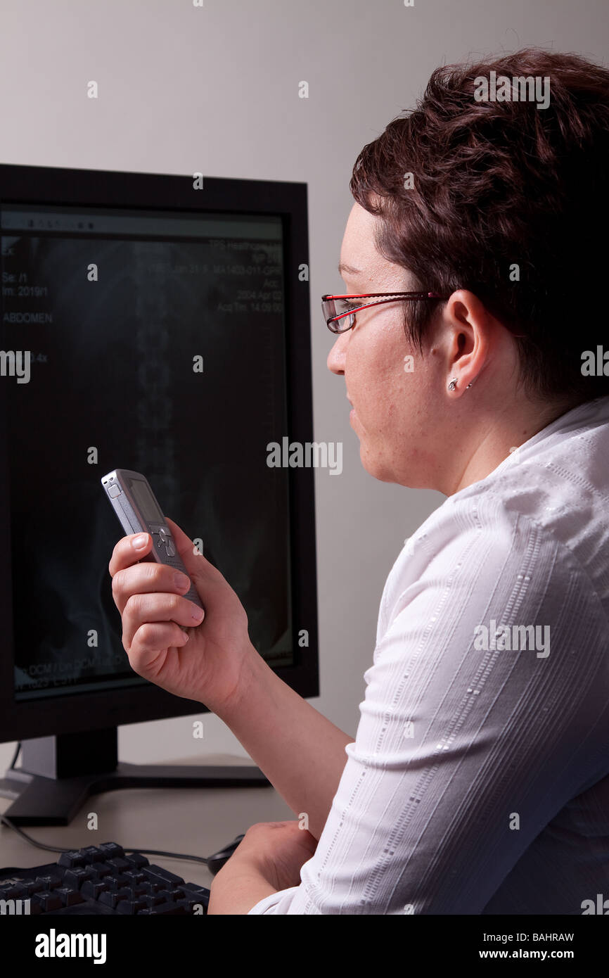 Femme affichage des images par rayons X sur un écran plat moniteur PACS. Lumière propre de droit approprié pour illustrer la situation médicale ou il Banque D'Images
