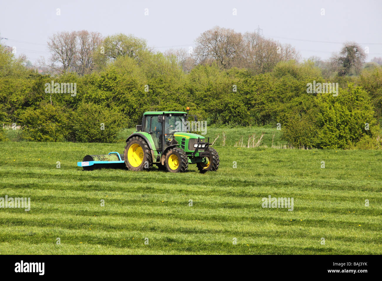 Tracteur John Deere à l'aide d'un rouleau pour aplatir l'herbe Banque D'Images