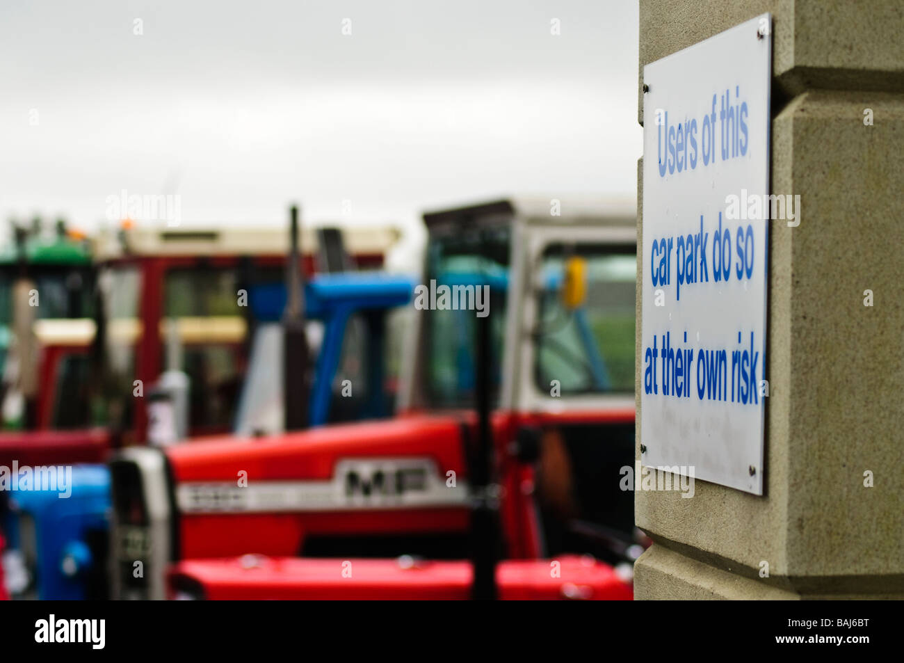 Inscrivez-vous dans le parking "Les utilisateurs de ce parking, le font à leurs propres risques' avec les tracteurs de ferme stationné à l'arrière-plan. Banque D'Images