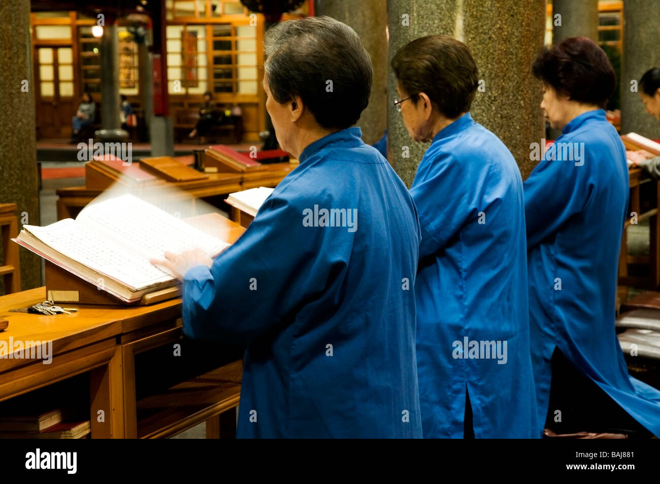 Trois femmes asiatiques âgées vêtues de robes bleu priant et chantant dans temple à Taipei, Taiwan Banque D'Images