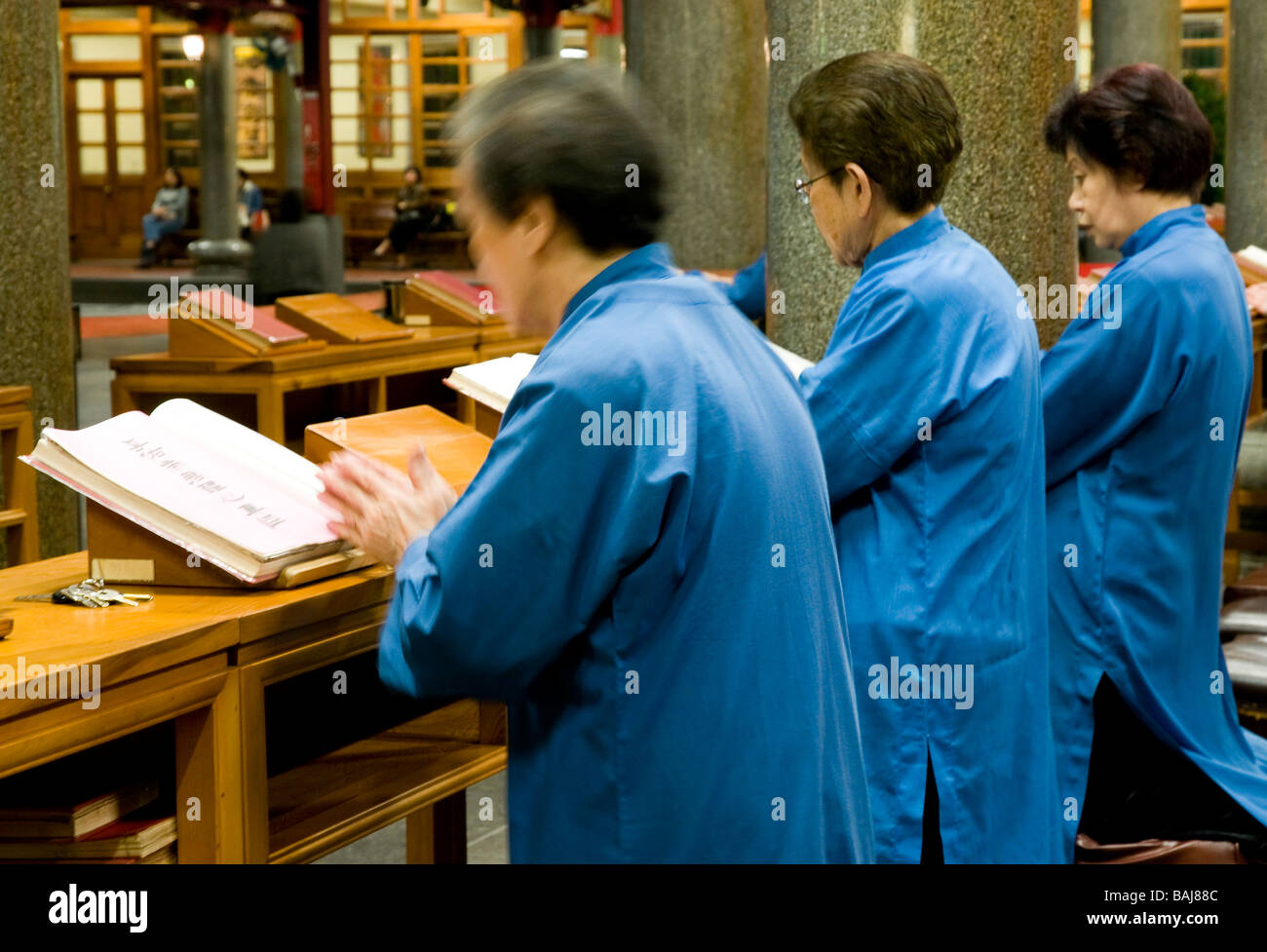Trois femmes asiatiques âgées vêtues de robes bleu priant et chantant dans temple à Taipei, Taiwan Banque D'Images