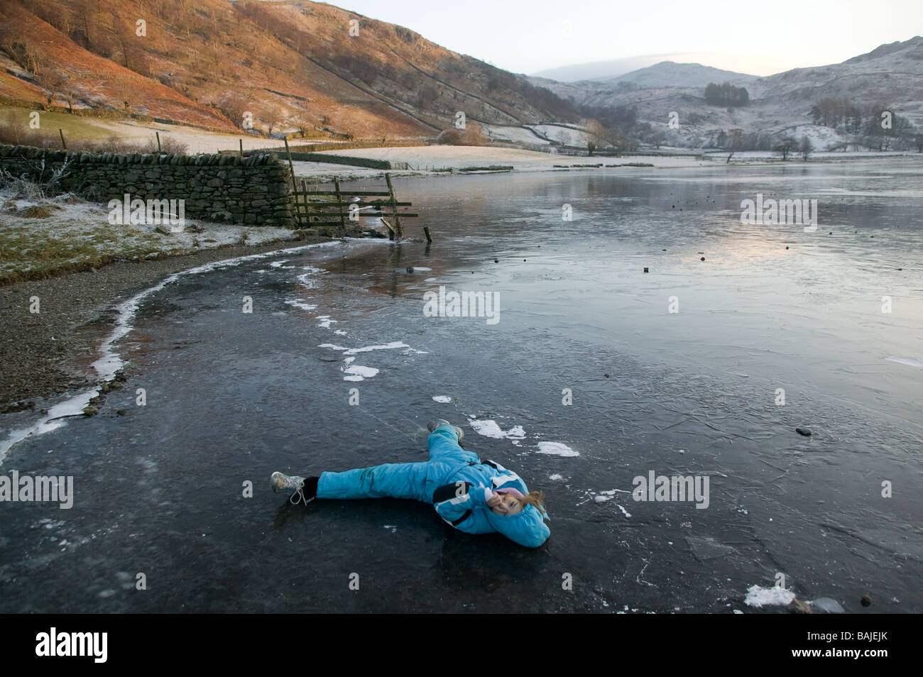 Jeune fille jouant sur la glace d'un lac gelé dans le Lake District, Cumbria, Royaume-Uni Banque D'Images