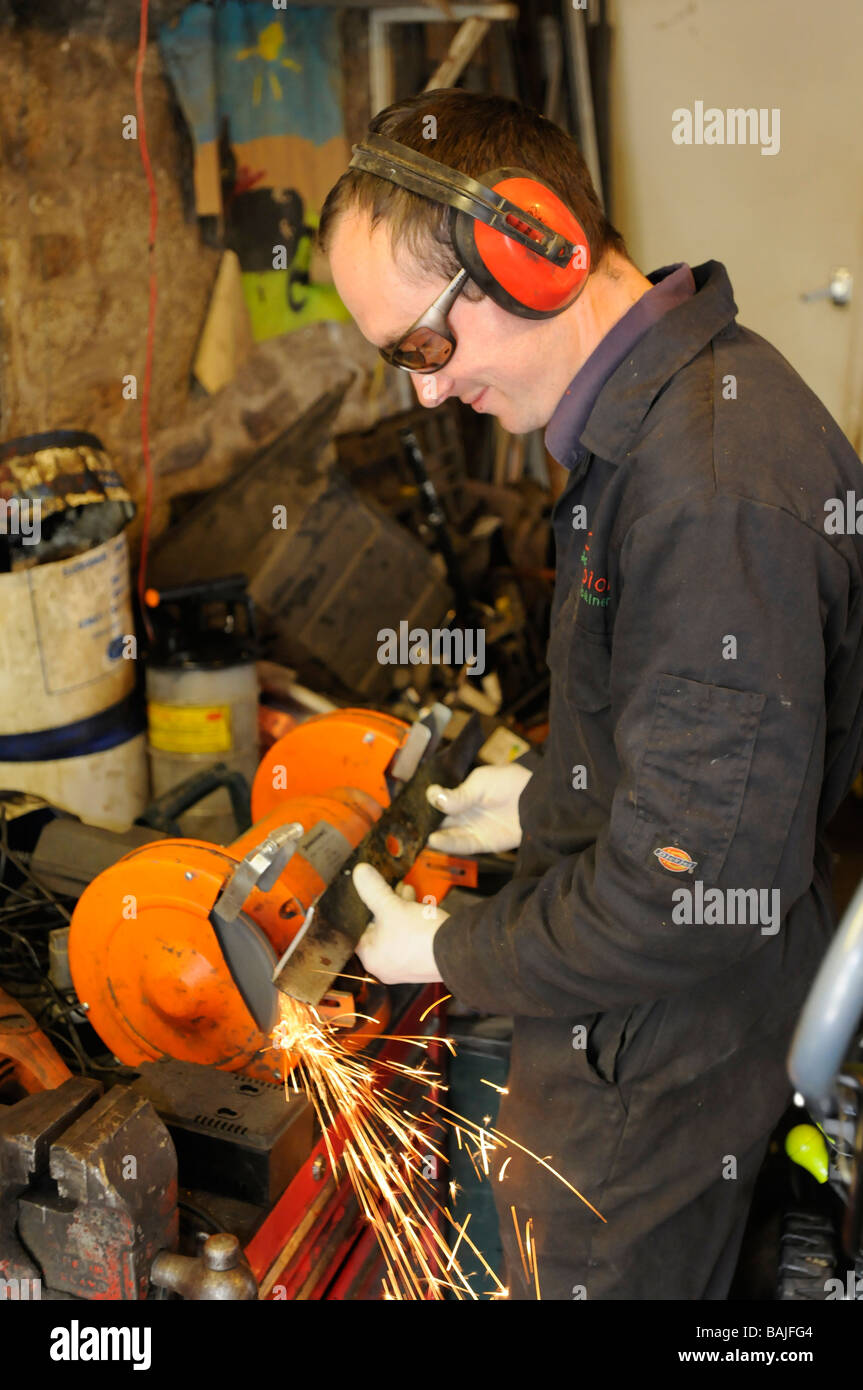 Un homme répare une tondeuse à lame dans son atelier Banque D'Images