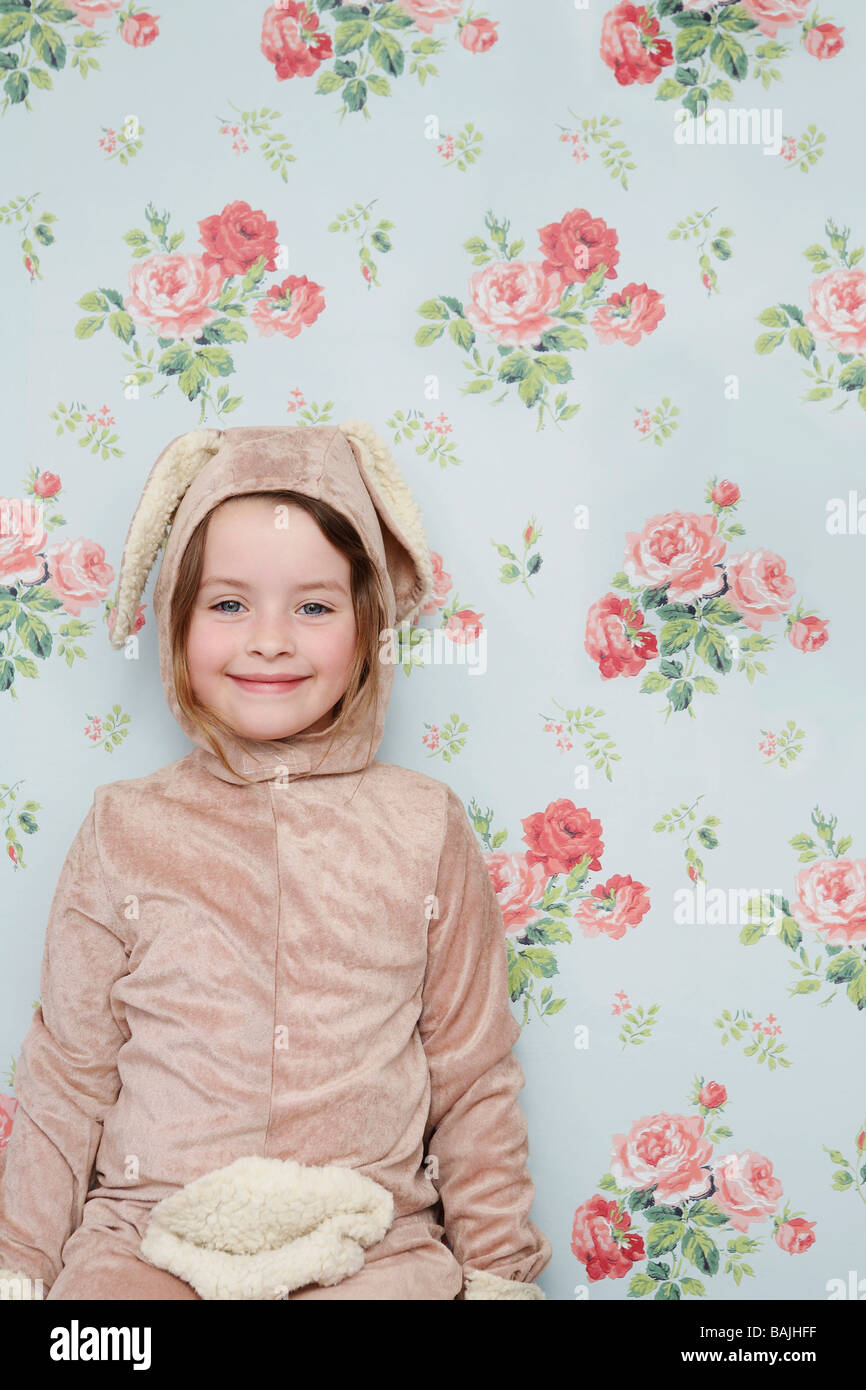 Portrait of young girl (5-6) en costume de lapin contre le papier peint avec motif floral Banque D'Images