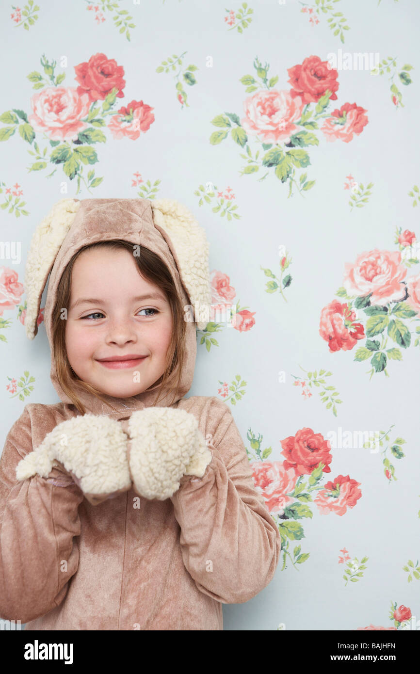 Portrait of young girl (5-6) en costume de lapin contre le papier peint avec motif floral Banque D'Images