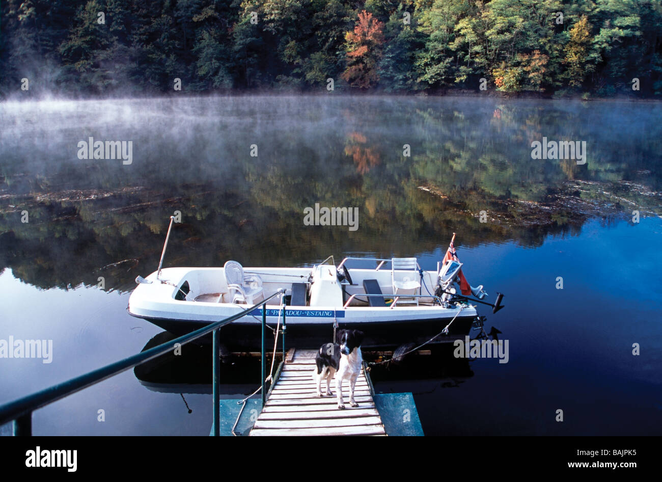 Réflexions brumeuses sur le Lot de la rivière et le stade d'atterrissage avec bateau amarré où le chien attend pour aller pêcher, Aveyron France Banque D'Images