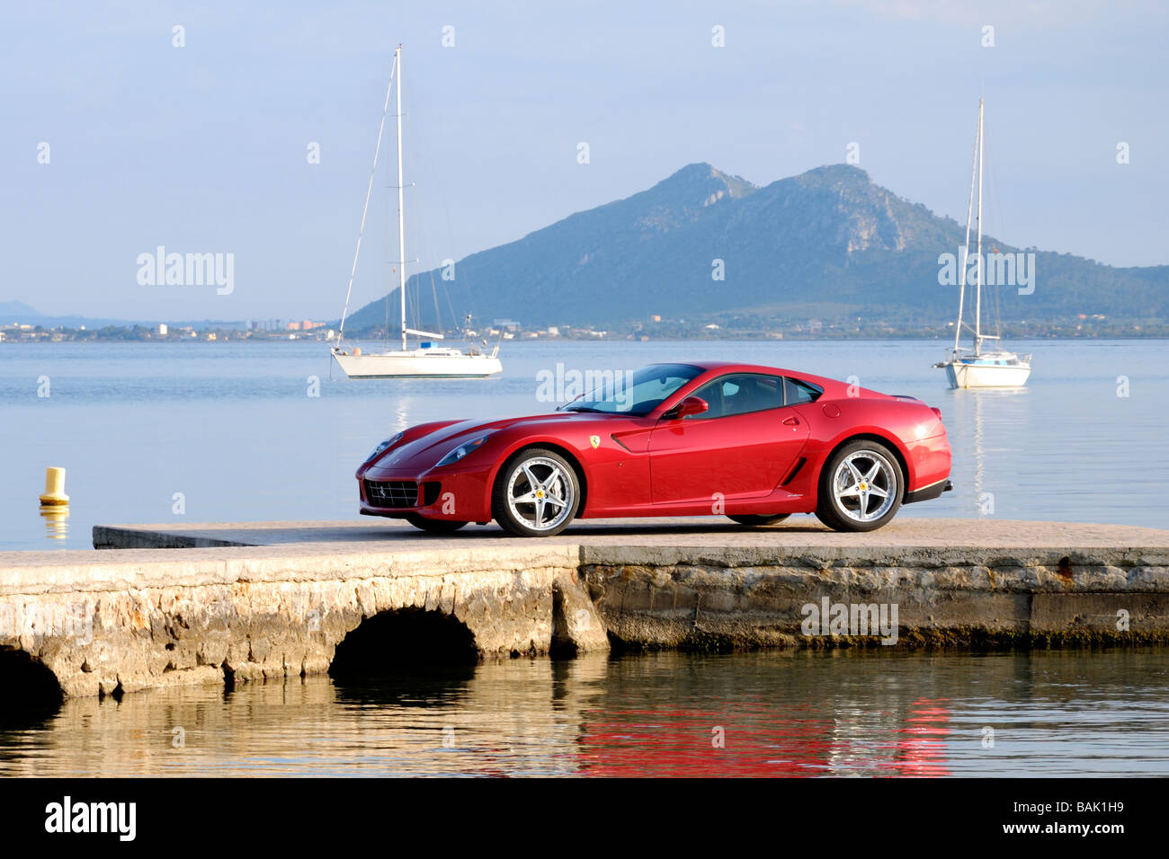 2009 rouge Ferrari sur dock méditerranéenne privée dans la baie de Pollensa avec les yachts et les montagnes de Tramuntana dans l'arrière-plan Banque D'Images