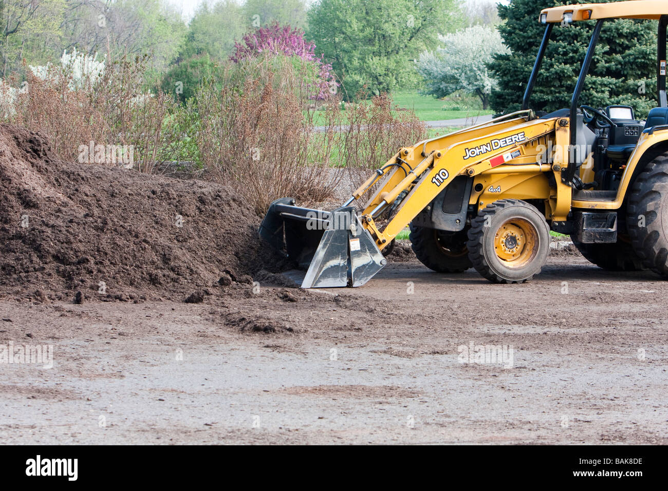 Un tracteur John Deere jaune avec un tas de paillis. La chargeuse pelleteuse avant. Banque D'Images