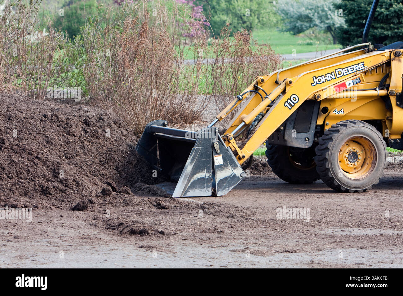 Un tracteur John Deere jaune avec un tas de paillis. La chargeuse pelleteuse avant. Banque D'Images