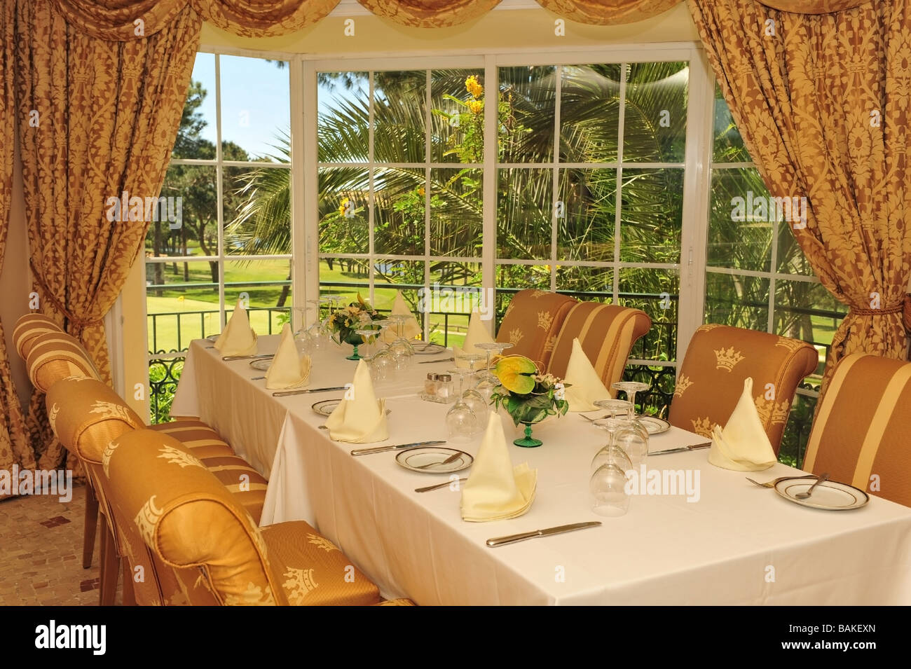 Table de dîner de luxe déjà mis en place en vue de la golf de Pinheiros Altos à travers la fenêtre. Banque D'Images