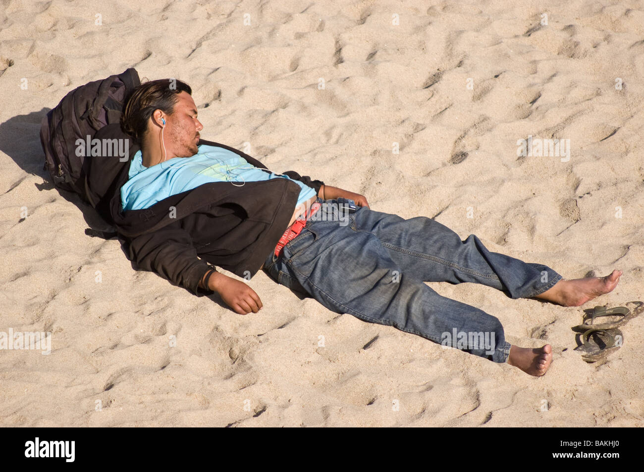 Un homme de prendre une sieste sur le sable à Huntington Beach, Californie Banque D'Images