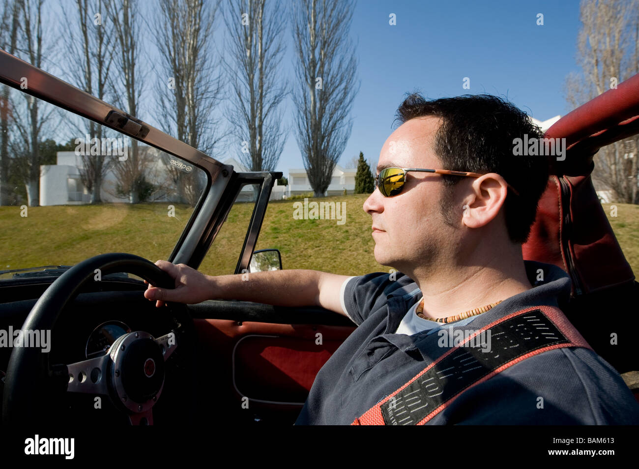 Homme conduisant une voiture de sport MG Midget classique convertible avec le toit vers le bas sous le soleil d'été Banque D'Images