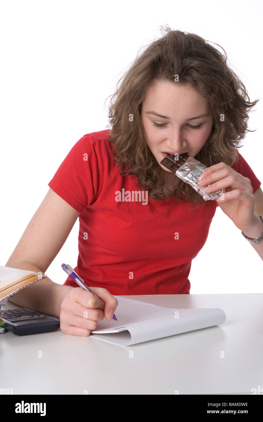 Teenage girl faire ses devoirs et manger du chocolat Banque D'Images