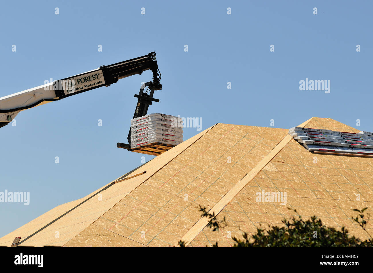 Un chariot élévateur fournit des matériaux de toiture en haut d'une nouvelle maison en construction. New York, USA. Banque D'Images