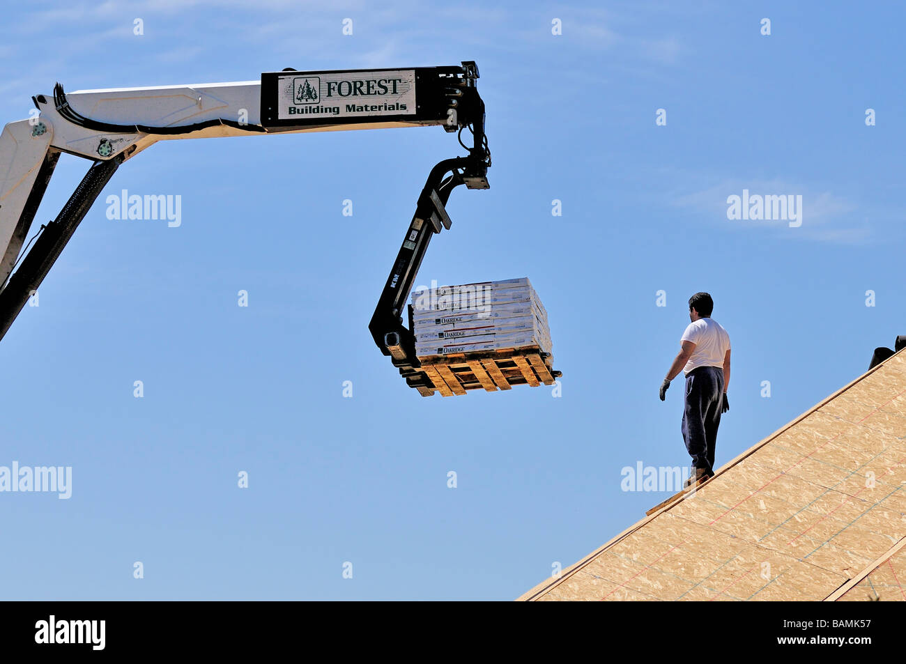 Un travailleur de la construction diriger l'exécution de matériau de couverture par un chariot élévateur. Oklahoma City, Oklahoma, USA. Banque D'Images