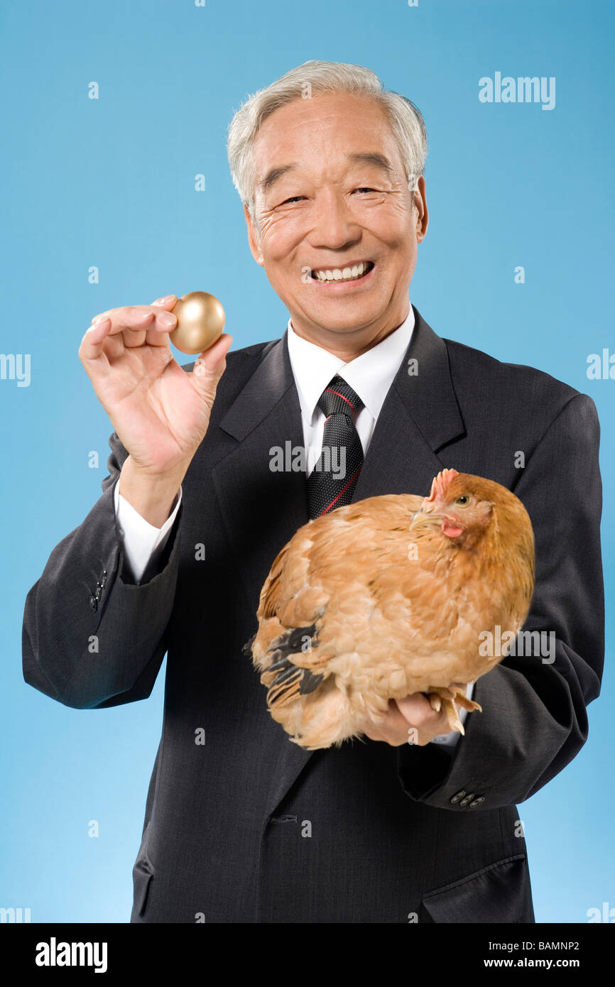 Businessman Holding un poulet et oeufs d'or Banque D'Images