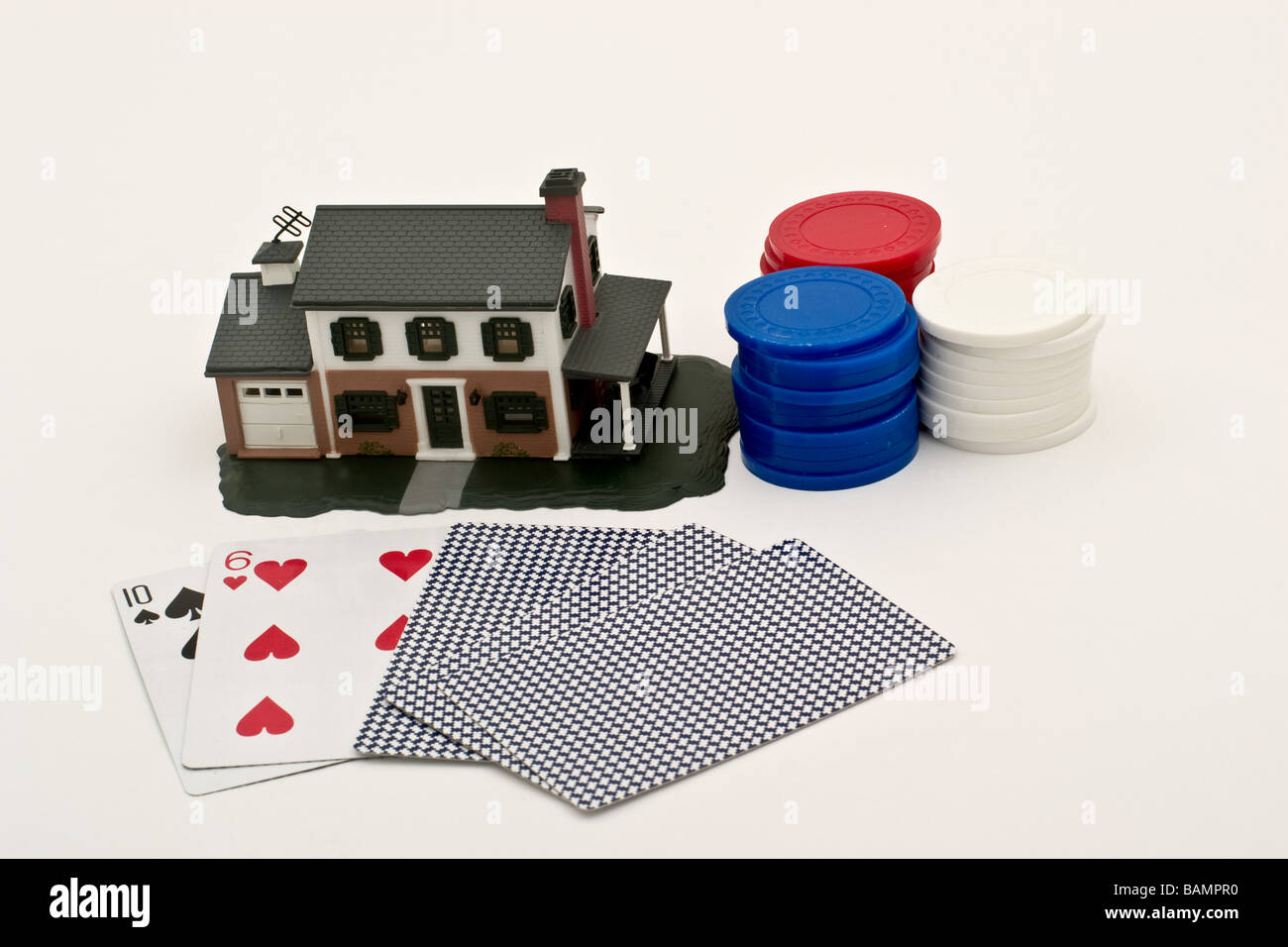 Main de poker avec trois piles de jetons en plastique avant d'une réplique d'une maison de banlieue Banque D'Images