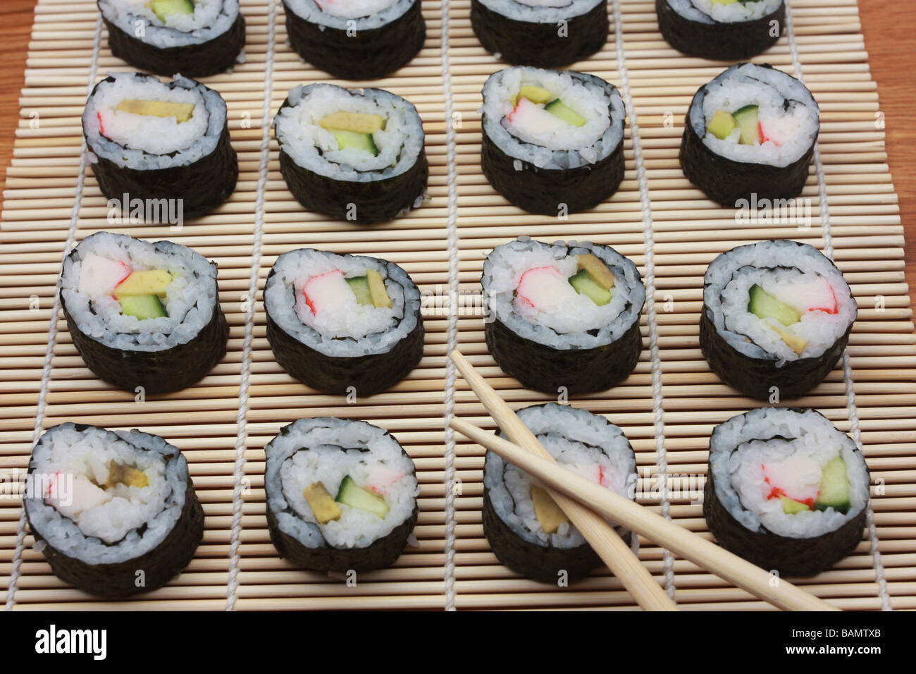 Rouleaux de sushi maki japonais traditionnel sur un tapis avec des baguettes de bambou Banque D'Images